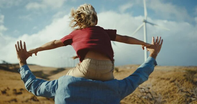 Father and son looking towards a clean and sustainable energy future, wind turbines on the hill side, dreaming of a sustainable economy, father and son bonding together