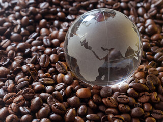 Glass earth globe Africa and Asia in center closeup among coffee beans background