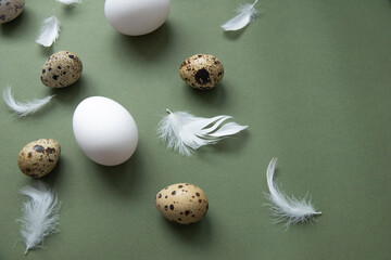 Stylish eggs pattern. Happy Easter. Flat-lay image of eggs and feathers on a green background....