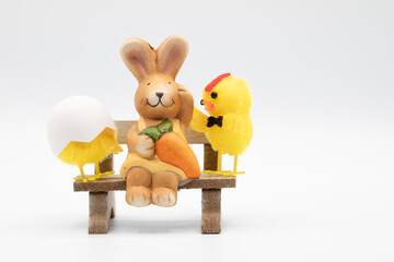 A bunny easter rabbit sitting on a bench, sniffing, looking around, on white background. Lovely bunny easter rabbit. easter bunny with easter eggs background