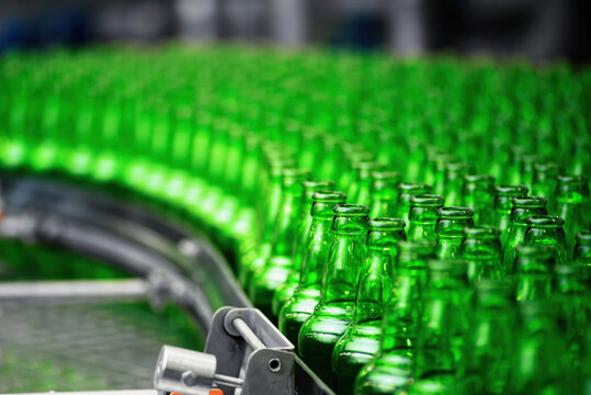 Automated conveyor line in a brewery. Rows of green glass bottles on a conveyor belt. Industrial brewery