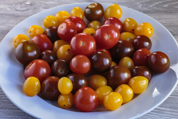 Multicolored tomatoes of different varieties in a dish. Fashionable vegan food.