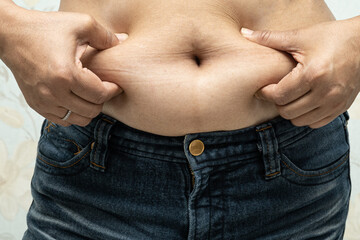 Naklejka premium Overweight Asian woman show fat belly at office.
