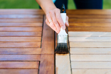 renovation of a garden table with a paintbrush and oil by a young woman on the terrace - 419679811