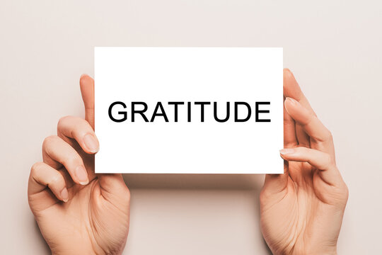 Female hands hold card paper with text Gratitude on a yellow background. Business and finance concept