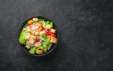 Classic caesar salad with crispy crackers on a dark background.