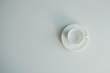 White ceramic empty cup on saucer top view, copy space