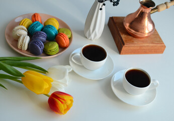 Two cup of coffee, multicolored macaroons, turkish coffee pot on white background, top view