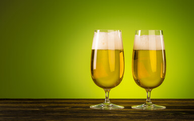 Two Glass of Beer on natural wooden table on green background. Craft Beer festival. Beer with foam in a pub. Alcohol drink. Macro photography. Close-up with copy space.