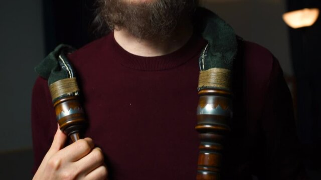 Portrait of a bearded man with pipes on his shoulders. He looks into the camera. Focus of attention of a creative person. Camera movement.