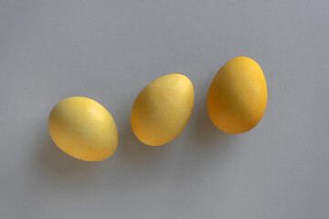 Three yellow eggs on the grey background.
