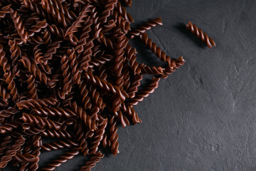 Organic uncooked Buckwheat Fusilli pasta on dark background. Wholegrain gluten free noodles....