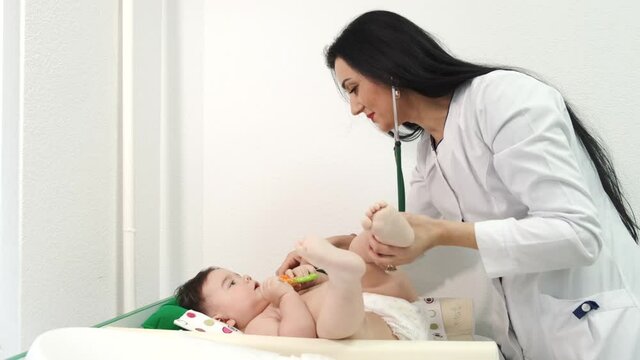 Newborn baby get examine by pediatrician hold stethoscope, pediatric doctor monitoring heart pulse rate adorable infant in clinic, pediatrician with child concept.