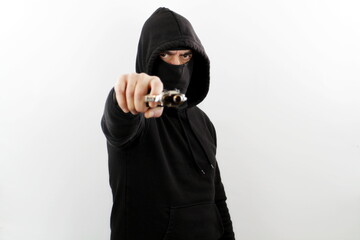 Criminal man wearing balaclava and hoodie pointing a gun at the camera. Crime concept