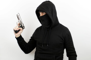 Man wearing balaclava and hoodie holding pistol over isolated white background. Crime concept