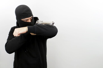 Criminal man wearing balaclava holding pistol, standing shooting with a gun