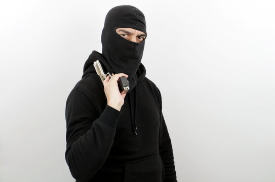 Man wearing balaclava holding pistol over isolated white background. Crime concept