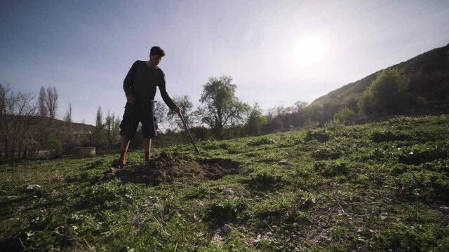 Joven agricultor cava agujero en el huerto con una azada con calidad cinematogr&aacute;fica a c&aacute;mara lenta 