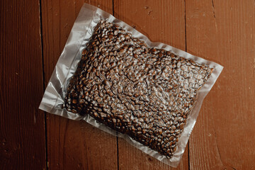 fresh roasted coffee beans packed in vacuum sealed bag on plank background