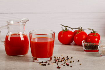 Fresh tomato juice in a glass with tomatoes salt and pepper on a dark background. Vegetable tomato drink for a healthy diet on a gray background. Top view.