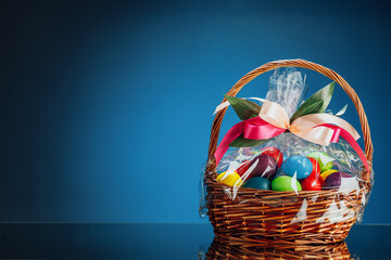 Easter gift basket with multicolor eggs, blue background with copy-space