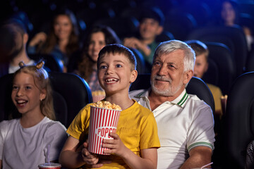 Grandfather with grandson on knees in cinema.