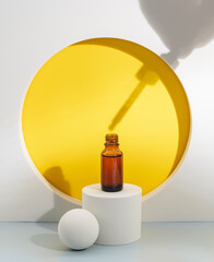 Glass cosmetic bottle with oil or serum for skin care on special podium on yellow background. Shadows Natural skin care concept. Harsh shadows
