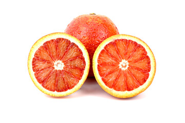 Two halves of a red ripe orange. There is a whole unpeeled orange behind.