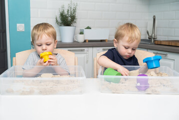 two blonde boys twins play with kinetic sand at home. Creative play for kids