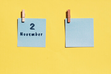 November 2. 2nd day of the month, calendar date. Two blue sheets for writing on a yellow background. Top view, copy space. Autumn month, day of the year concept