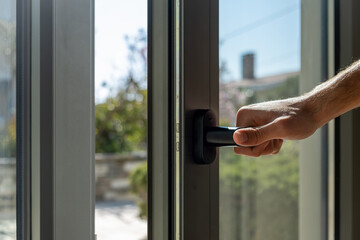 Aluminum window frame detail. Male hand opens the metal door closeup view. © Rawf8