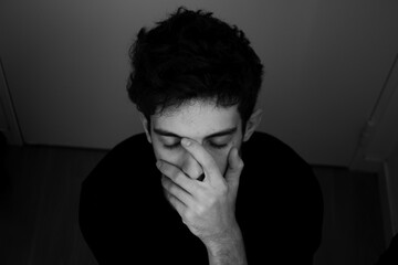 Teenager portrait sadness takes his head in his hands black and white