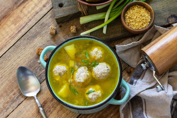 Healthy and diet food. Soup with meatballs and bulgur on a wooden table. Copy space.