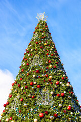 Christmas tree with red and yellow balls against the blue sky