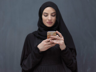 Young muslim businesswoman in traditional clothes or abaya using smartphone