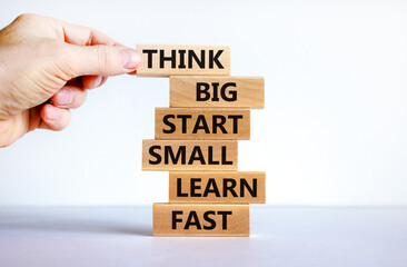 Think big start small symbol. Words 'Think big start small learn fast' on wooden blocks on a beautiful white background. Businessman hand. Business, motivational and think big start small concept.