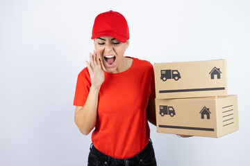 Young beautiful woman wearing courier uniform holding delivery packages shouting and screaming loud...