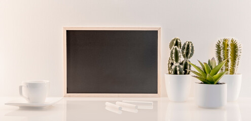 Modèle de tableau noir en ardoise avec espace vide pour logos, inscription publicitaire. Cadre en mode paysage sur un espace de travail avec une tasse et des craies.	