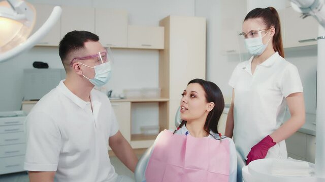 Communication of the patient with the doctor and the assistant doctor in the dental clinic. The patient is a pretty girl who asks questions to the doctor. Modern medicine in dentistry