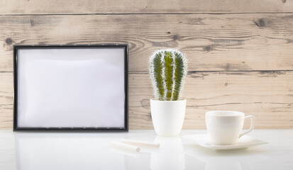 Modèle de cadre photo blanc avec espace vide pour logos, inscription publicitaire. Cadre en mode paysage sur un espace de travail avec une tasse. Ambiance zen.	
