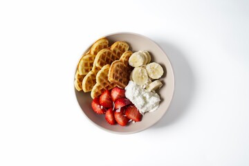 Bowl with Belgian waffles, Greek yogurt, fresh strawberries, banana and coconut flakes