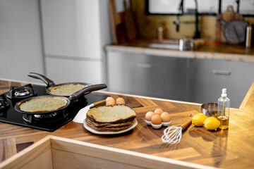 Preparing pancakes for a breakfast, food ingredients and fried pancakes on the wooden table on the kitchen at home