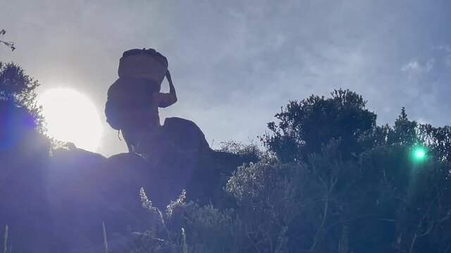 Tanzanian porters carrying a bags on their heads on the famous climbing route on Barranco Wall on the way to to Karanga camp near Moshi, Tanzania. Sun rays backlight 4K video.