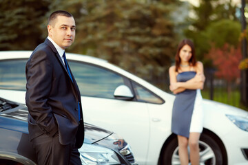 portrait of a young couple on a date standing near cars.