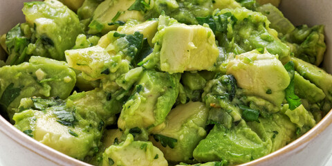 Close-up view of chunky guacamole in ceramic bowl. Mexican cuisine.