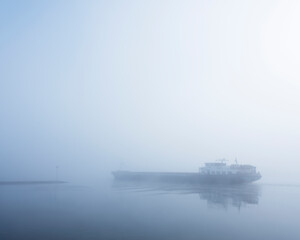 Obraz premium barge in the mist on river rhine near utrecht in holland