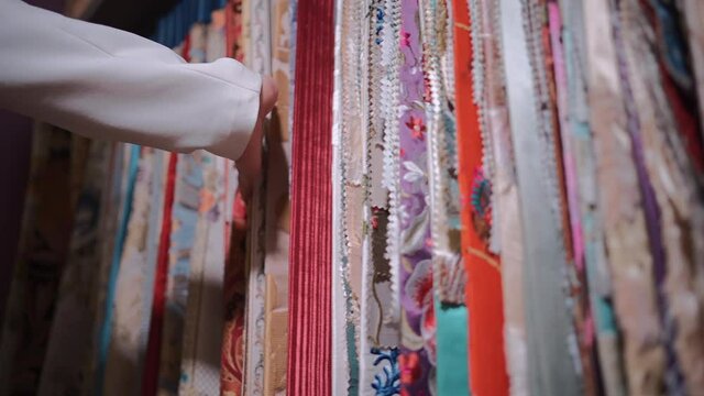 closeup of female hand choosing fabric cloth for curtain at showroom or shop