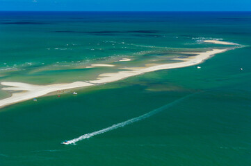 Sandbank in the bluish green sea, with boats and people, on the beach of Catuama, near Recife,...