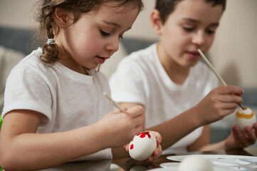 Children painting eggs for Easter. Traditional religious event.