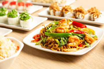 Table with Japanese food sushi, noodles and rice with vegetables.